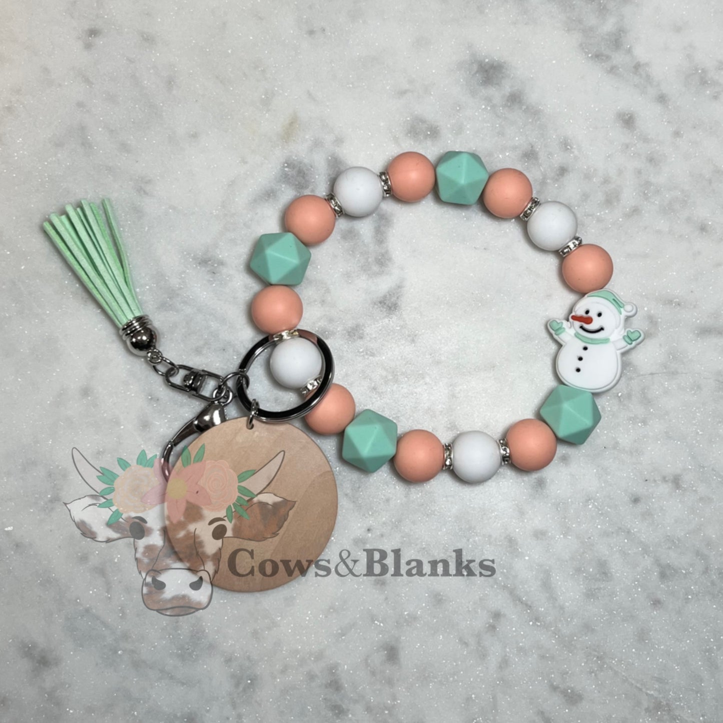 CHRISTMAS: SNOWMAN SILICONE BEAD WITH WHITE, PEACH AND MINT GREEN ACENTS BEADED STRETCH WRISTLET BRACELET WITH WOODEN DISC AND MINT TASSEL