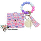 Wallet/Wristlet with Butterflies Covering the Cardholder With a Coordinating Silicone White, Pink and Purple Wristlet with Wooden Disc and Matching Tassel