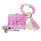Wallet/Wristlet with White with Dark and Light Pink Heart Cardholder with a White, Pink, and Light Pink Silicone Beaded Wristlet with a Wooden Accent Bead, Gold Hardware, Matching Tassel, and a Wooden Disc